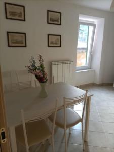 a white dining room table with a vase of flowers on it at Appartamento Casa Margi in Ameglia +8 photos
