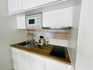 a white kitchen with a sink and a microwave at Estudio”CasaTeva”(PIEpista-Vistas-Wiffi-Netflix…) in Pas de la Casa