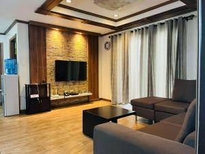 a living room with a couch and a flat screen tv at Gab's CozyHome at Bonbel Condo, Botanical Gardens Baguio in Baguio