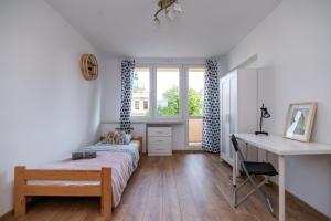 a bedroom with a bed and a desk and a window at Regem Pokoje Nowogrodzka in Warsaw
