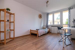 a bedroom with a bed and a desk and a table at Regem Pokoje Nowogrodzka in Warsaw