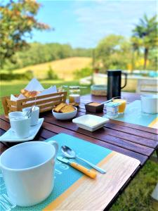 einem Holztisch mit Tassen und Teller mit Lebensmitteln darauf in der Unterkunft Maison Lacourrège in Urgosse