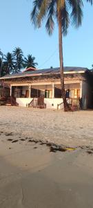 a building on the beach with a palm tree at ALFA Beach Front Lodge in El Nido