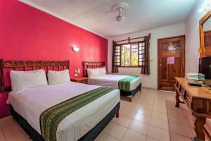 a bedroom with two beds and a red wall at Hotel San Juan Mérida in Mérida