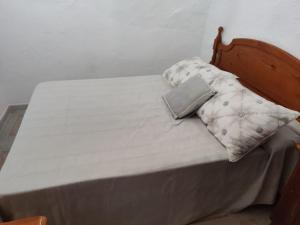 uma cama com uma cabeceira em madeira e 2 almofadas em La Casilla: Casa acogedora a los pies de la Atalaya. em Níjar