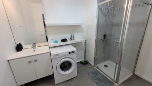 een badkamer met een wasmachine en een douche bij Flat for 6 persons 10 minutes from CDG Airport in Le Blanc-Mesnil