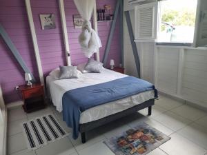 una camera con un letto con una parete viola di Fleur d'Hibiscus a Saint-Louis