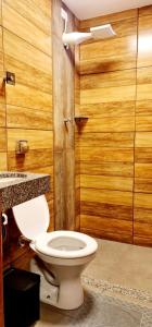 a bathroom with a toilet and a wooden wall at Hotel Platina in Juiz de Fora