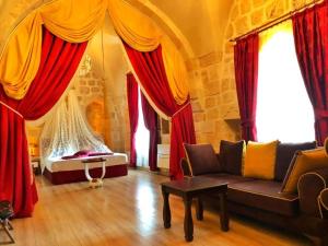 Tuğhan Hotel في ماردين: غرفة معيشة مع ستائر حمراء وأريكة