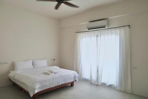 een slaapkamer met een bed, een plafondventilator en een raam bij SUNME Inn in Magong
