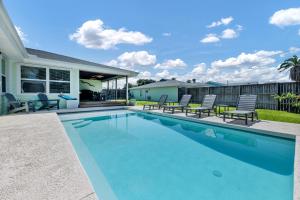 a swimming pool with chairs and a house at The Turtle Dolphin in Port Aransas