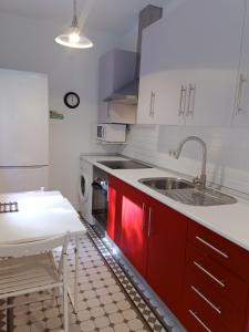 uma cozinha com armários vermelhos, um lavatório e uma mesa em Tambre em Brion