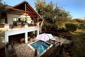 a house with a swimming pool and an umbrella at Eden Safari Country House in Marloth Park