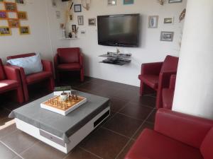 ein Wartezimmer mit roten Stühlen und einem Flachbild-TV in der Unterkunft Maison de vacances au calme entre St Malo et Cancale in Saint-Méloir-des-Ondes