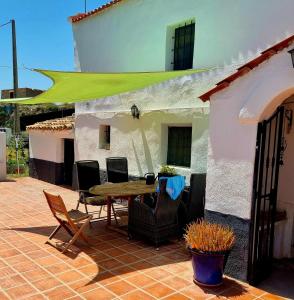 un patio con mesa y sillas frente a una casa en Cortijo naturista con vistas -Clothing optional en Oria