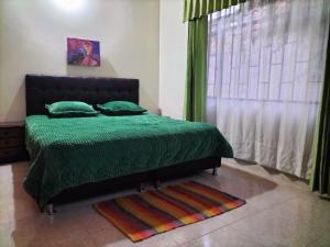 um quarto com uma cama verde e uma janela em CASA LA PRADERA em Paipa