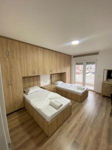 two beds in a room with wooden cabinets and a television at APARTMENT Ortakoll prizren 2 bedroom in Prizren