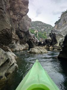 a green kayak in a river between rocks at Hostel Le Diablotin in Saint-Jean-de-Fos