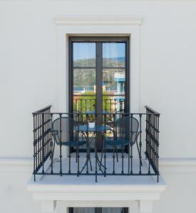 een balkon met een tafel en stoelen en een raam bij Argostoli Essence Suites in Argostoli