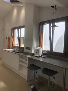 eine Küche mit einer Theke mit zwei Hockern und zwei Fenstern in der Unterkunft Antiga Biblioteca in Solsona