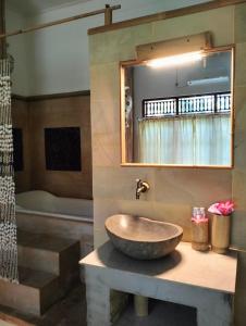 a bathroom with a bowl sink and a tub at Kaia Lovina Guest House Junior Suite in Lovina