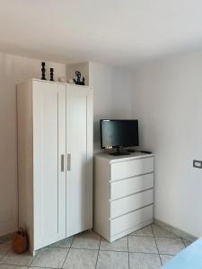 una camera da letto con TV e armadietto bianco di Terrazza delle rose a Nettuno