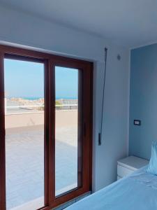 una camera da letto con porta scorrevole in vetro e vista sulla spiaggia di Terrazza delle rose a Nettuno