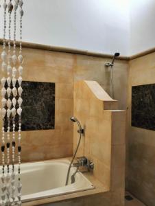 Kaia Lovina Guest House Junior Suite في لوفينا: حمام مع حوض استحمام ودش