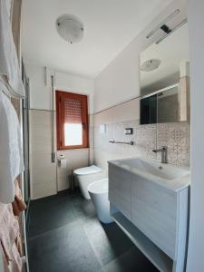 La salle de bains blanche est pourvue d'un lavabo et de toilettes. dans l'établissement Terrazza delle rose, à Nettuno