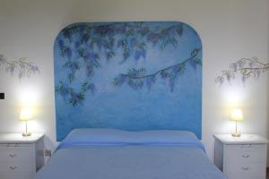 Un dormitorio con una cama azul con una pintura en la pared en Poggio della Stella, en Blera