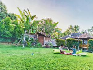 a man and a woman sitting on the grass at Kaia Lovina Guest House Junior Suite in Lovina