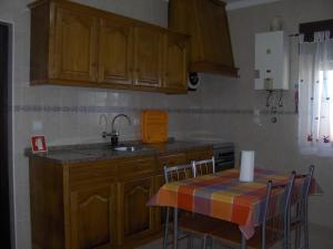 a kitchen with a sink and a table with chairs at Vivenda Palheiras in Roncão