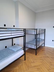 two bunk beds in a room with a wooden floor at Gingerbread Hostel in Toruń