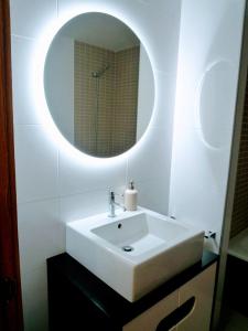 y baño con lavabo blanco y espejo. en Apartamento en Sada con piscina, en Sada