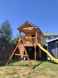 een houten speeltuin met een glijbaan en een huis bij PNW Home With Private Outdoor Getaway Space. in Des Moines