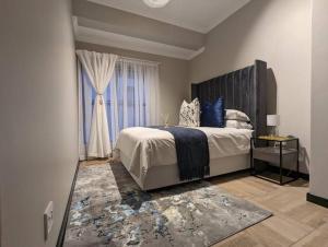 a bedroom with a large bed and a window at 1 Elizabeth Place - Beautiful self catering 2 bedroom unit next to Kyalami Racetrack with free WiFi - swimming pool gym and restaurant - Perfect for a small family in Midrand Waterfall in Midrand +21 photos