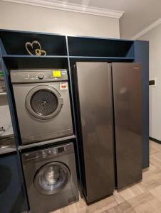 a kitchen with a refrigerator and a washing machine at 1 Elizabeth Place - Beautiful self catering 2 bedroom unit next to Kyalami Racetrack with free WiFi - swimming pool gym and restaurant - Perfect for a small family in Midrand Waterfall in Midrand