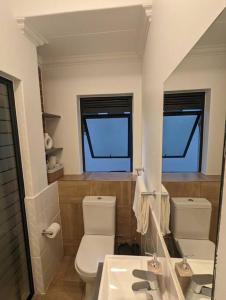 een badkamer met een toilet, een wastafel en een spiegel bij 1 Elizabeth Place - Luxury Executive Apartment, free Wi-Fi in Midrand