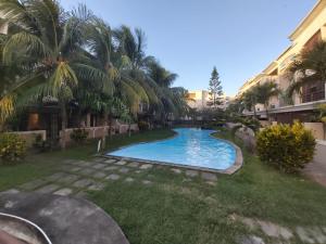 - une piscine au milieu d'une cour avec des palmiers dans l'établissement OTAKS1 Waterside stunning 4b villa 80 metres from the beach with all amenities nearby & a large pool, à Grand Baie