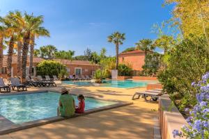 un hombre y un niño sentados junto a una piscina en Camping La Pinède Enchantée en Argelès-sur-Mer