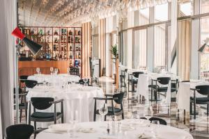 a restaurant with white tables and chairs and windows at Met Boutique Hotel in Zagreb