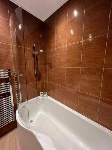 a bath tub in a bathroom with wooden walls at Spacious 2Bed/2Bath Flat next to London Eye in London