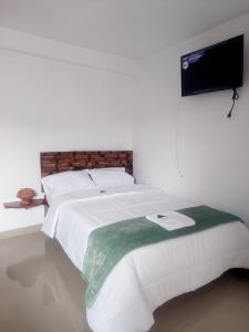 1 dormitorio con 1 cama blanca y TV de pantalla plana en ValMas en Chachapoyas