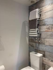 a bathroom with a toilet and towels on a wooden wall at Beautiful 1600’s loft apartment. in Ware