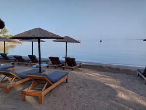 un grupo de sillas y sombrillas en una playa en new serenity villa aegina, en Aegina Town