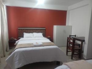 1 dormitorio con 1 cama grande y pared roja en ValMas en Chachapoyas