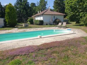 einen Pool mit zwei Stühlen und ein Haus in der Unterkunft Charmante propriété, piscine, Zoo Beauval, Châteaux Loire in Selles-sur-Cher
