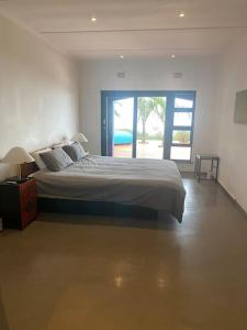 a bedroom with a large bed and a sliding glass door at Amasundu Beach House Trafalgar in Southbroom
