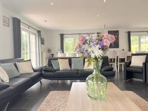 una sala de estar con un jarrón de flores sobre una mesa en Sur les Thiers en Lierneux