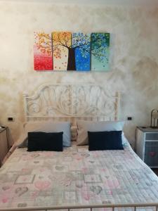 a bedroom with a bed with two paintings on the wall at Alla Contrada degli Asinelli in Colledanchise